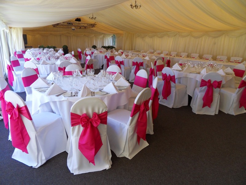 Cerise silk on bespoke tailored chair covers at Mill House Hotel marquee